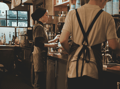 Coffee shop staff working behind the counter, preparing drinks for customers.